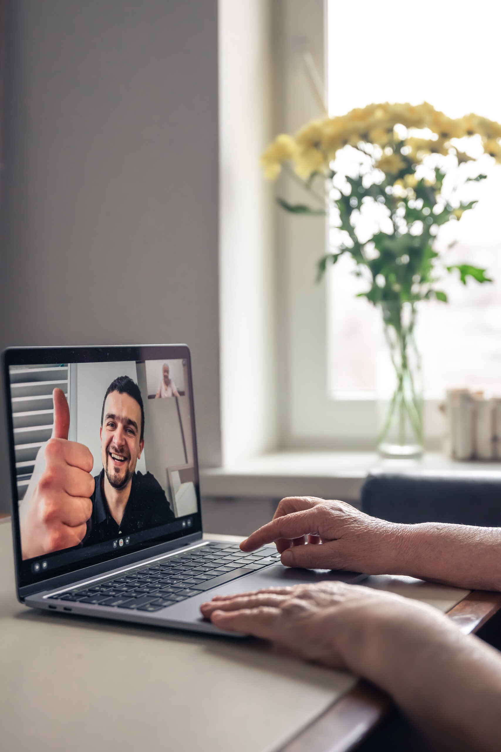 An old woman communicates with her son via video link through a laptop. A retired old woman communicates via video call with her son, uses laptop, technology concept.